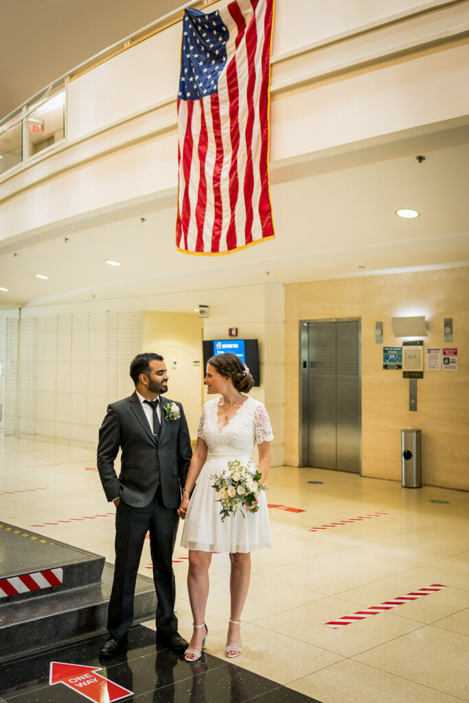Newlyweds under American flag in Bergen County courthouse lobby by Alex Kaplan Photography