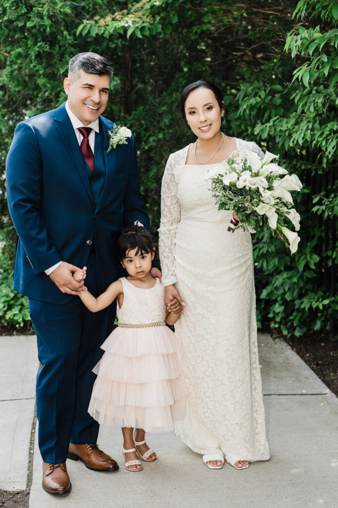 Bride, groom, and young daughter family portrait at Bergen County courthouse gazebo by wedding photographer Alex Kaplan