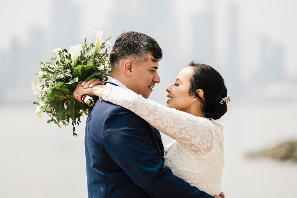 Romantic couple embrace at Waterside Restaurant with Manhattan skyline by Alex Kaplan Photography