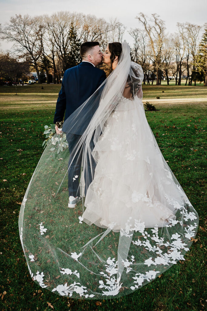 Bride and groom kissing with flowing cathedral veil at Thompson Park Jamesburg NJ winter wedding by Alex Kaplan Photography before 618 Restaurant Freehold Township reception