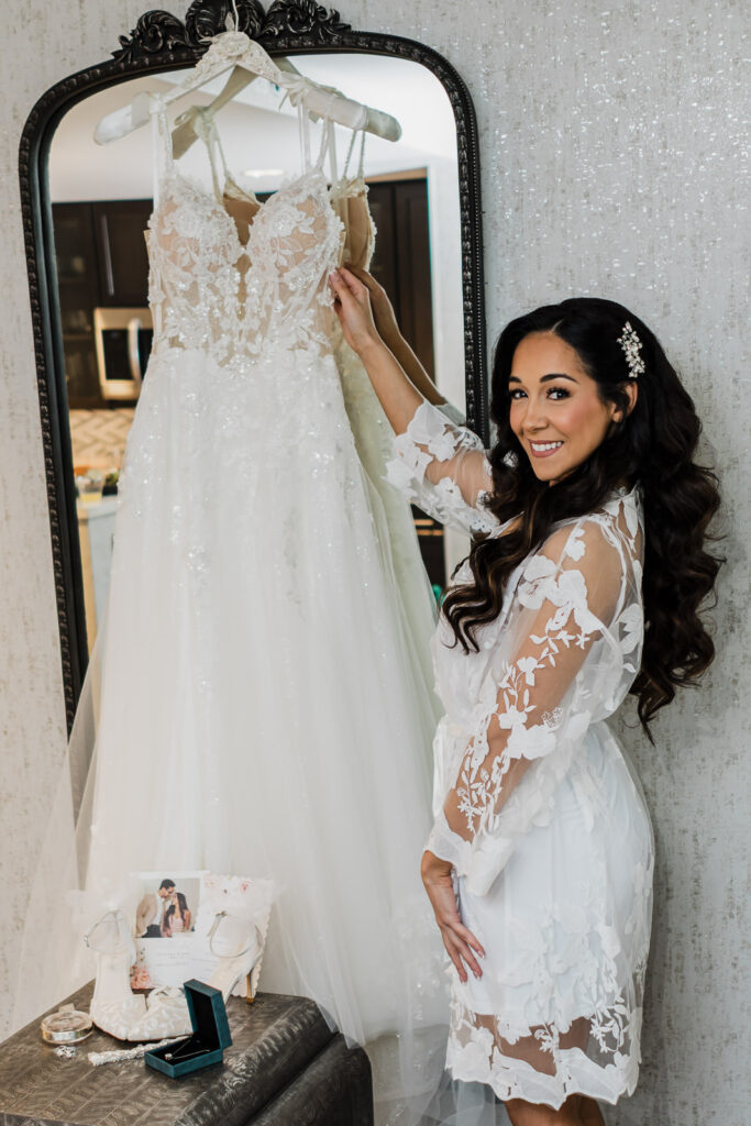 Bride Giovana in white floral robe holding wedding dress Hampton Inn Fairfield NJ