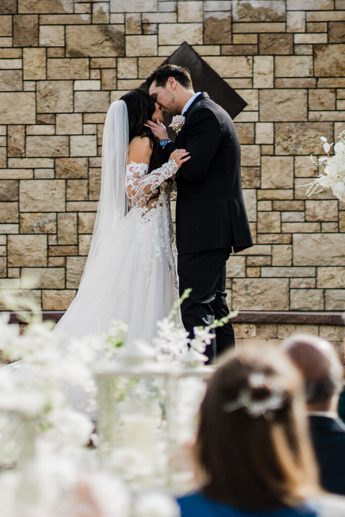 Couple kissing at stone wall ceremony space The Grand Totowa NJ