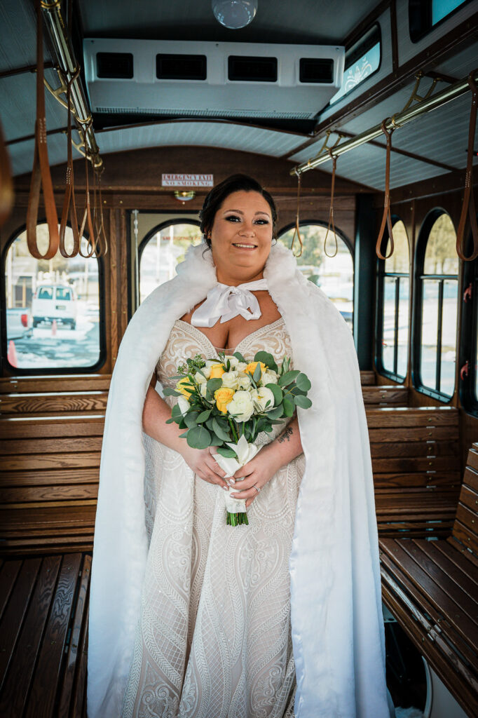 Bride with bouquet inside vintage trolley interior at Sussex County Fairgrounds winter wedding by Alex Kaplan Photography
