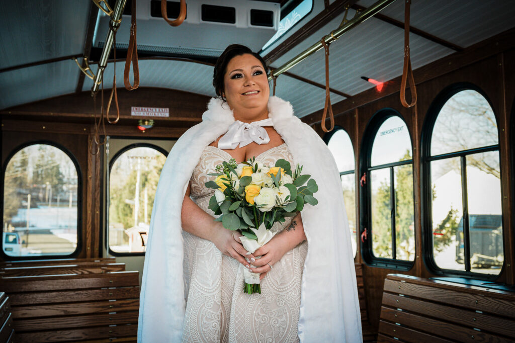 Bride in white fur cape inside vintage trolley at The Conservatory Sussex County Fairgrounds photographed by Alex Kaplan