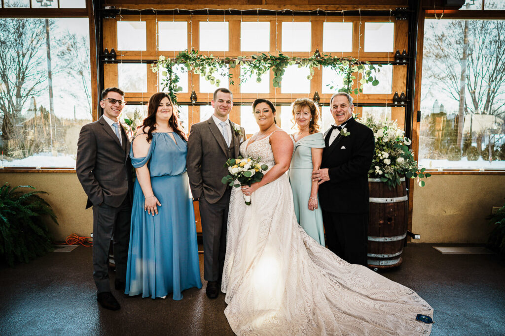 Extended family portrait in front of greenery backdrop at Sussex County Fairgrounds wedding by Alex Kaplan Photography