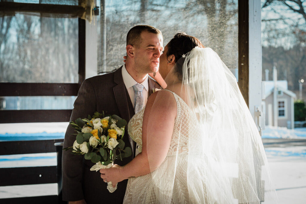 Bride and groom first look kiss at ice rink pavilion winter wedding photographed by Alex Kaplan