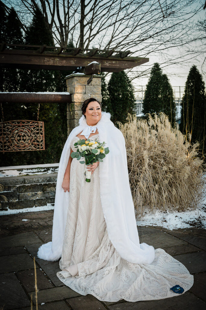 Winter bride portrait in white fur cape and lace wedding gown at The Conservatory at Sussex County Fairgrounds by Alex Kaplan Photography