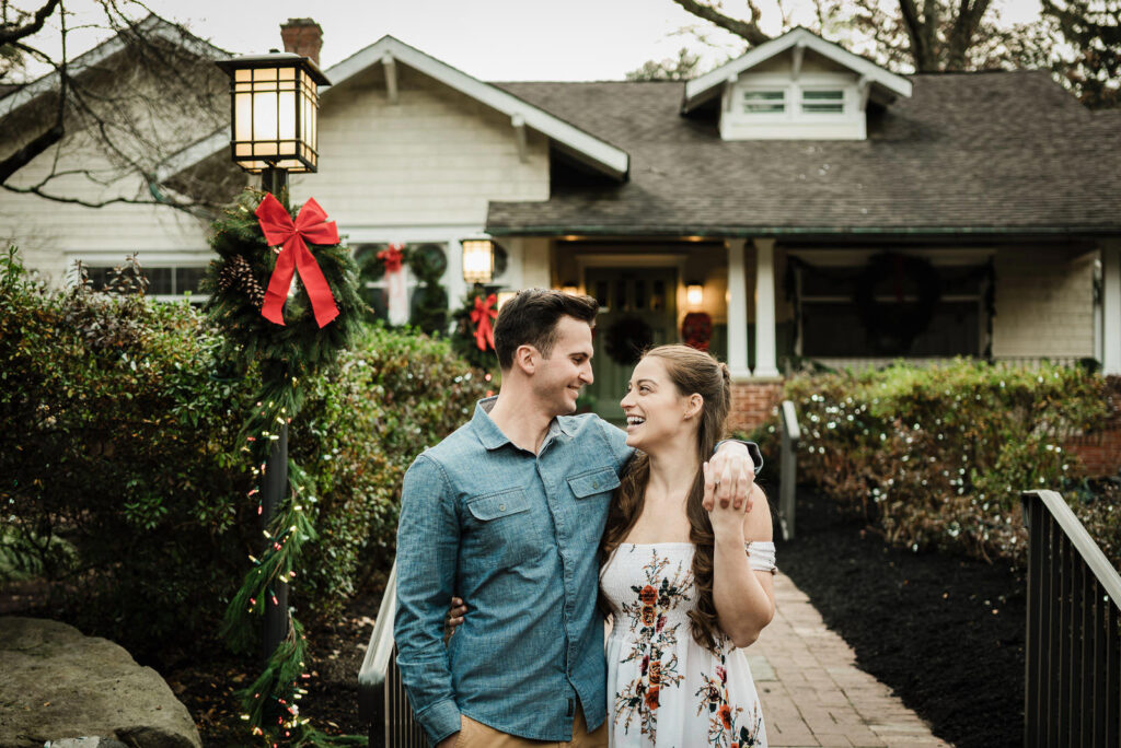 Newly engaged couple shows off ring in front of Christmas decorated Sayen House Hamilton New Jersey