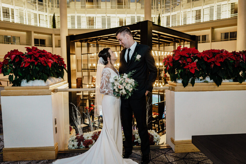 Couple with poinsettias at Hyatt Princeton winter wedding by Alex Kaplan Photography