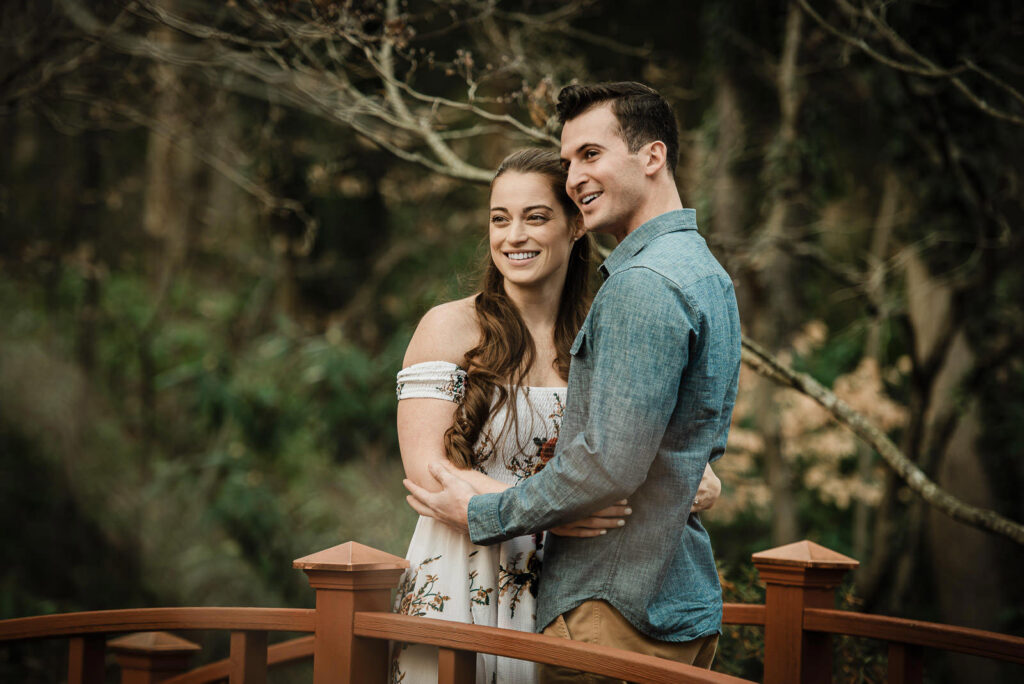 Happy engaged couple on wooden bridge at Sayen House and Gardens Hamilton New Jersey
