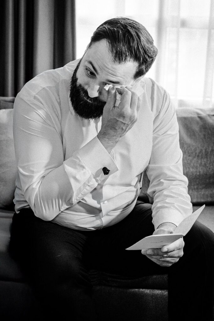 Groom John wiping tears while reading emotional letter from bride during getting ready at Westin Mount Laurel captured by Alex Kaplan Photography
