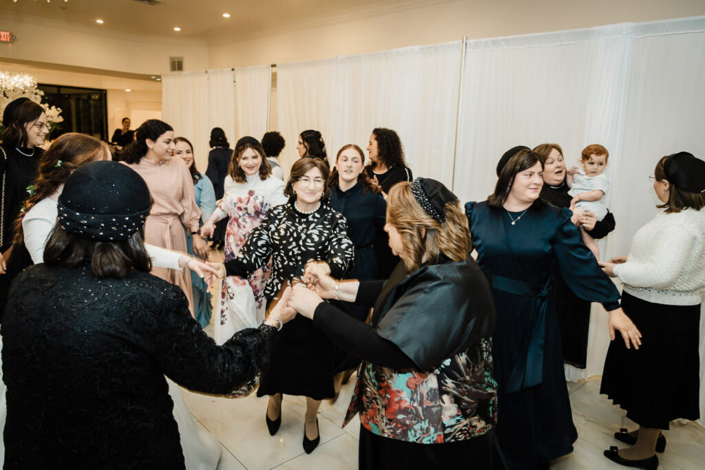 Groom lifted on chair during traditional hora dance at Riverview Ballroom Orthodox Jewish wedding