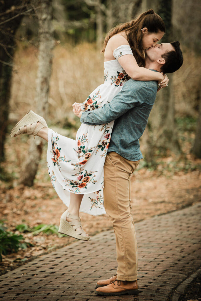 Groom lifts bride during romantic winter engagement photos at Sayen Gardens Hamilton Township NJ