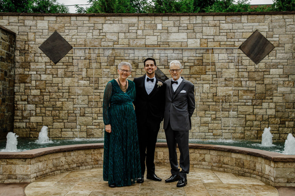 Groom Rob with parents Karen and John at fountain The Grand Totowa