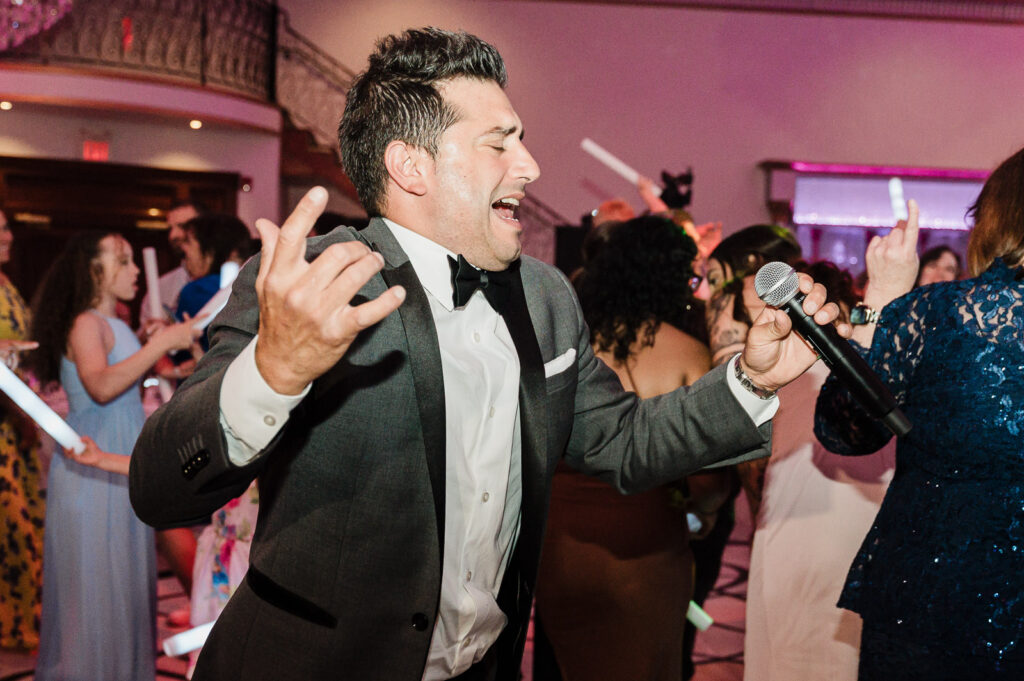 Wedding guest passionately singing karaoke during reception at Lucien's Manor captured by Bergen County photographer Alex Kaplan