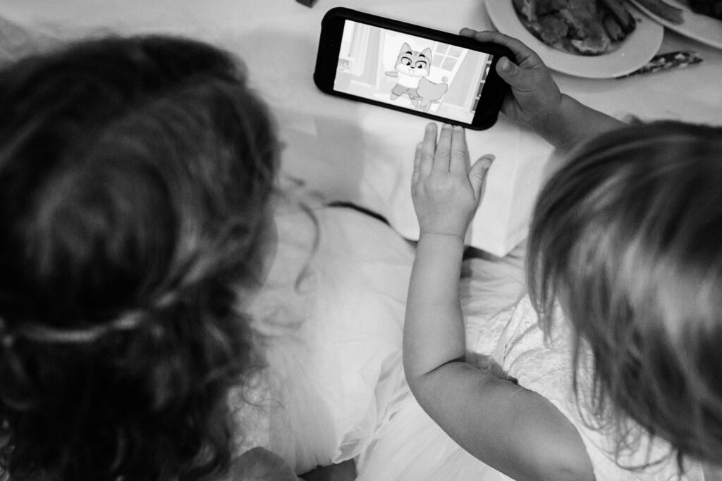 Children watching phone together during reception downtime at Lucien's Manor photographed by Alex Kaplan