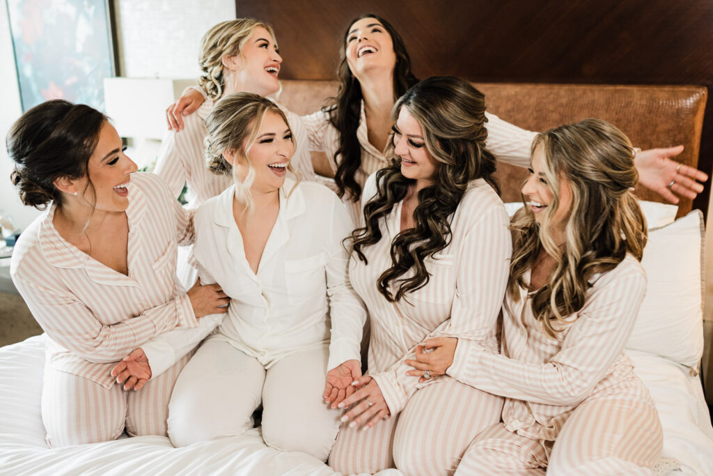 Bridesmaids in matching striped pajamas laughing together during getting ready photos at Westin Mount Laurel before Lucien's Manor wedding photographed by Alex Kaplan