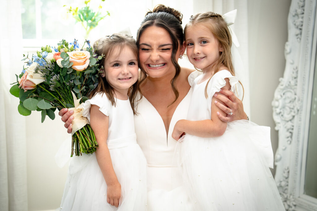 Bride embracing flower girls before ceremony at Mansion at Mountain Lakes