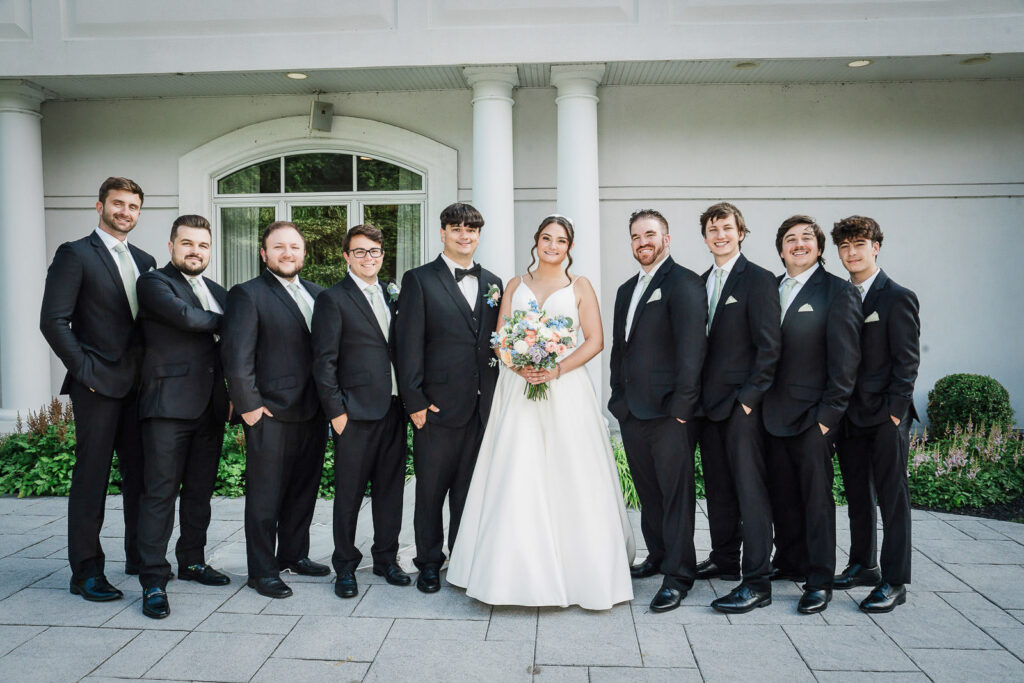 Bride posing with groomsmen outside Mansion at Mountain Lakes