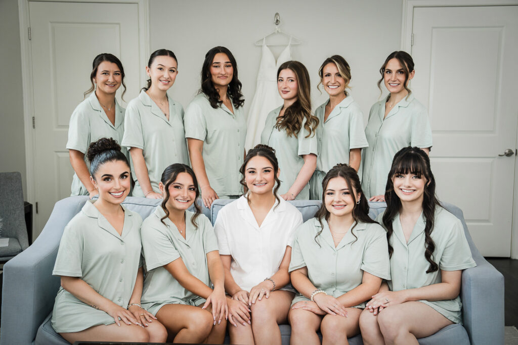 Bridesmaids wearing sage green pajamas gathered in bridal suite at Mansion at Mountain Lakes