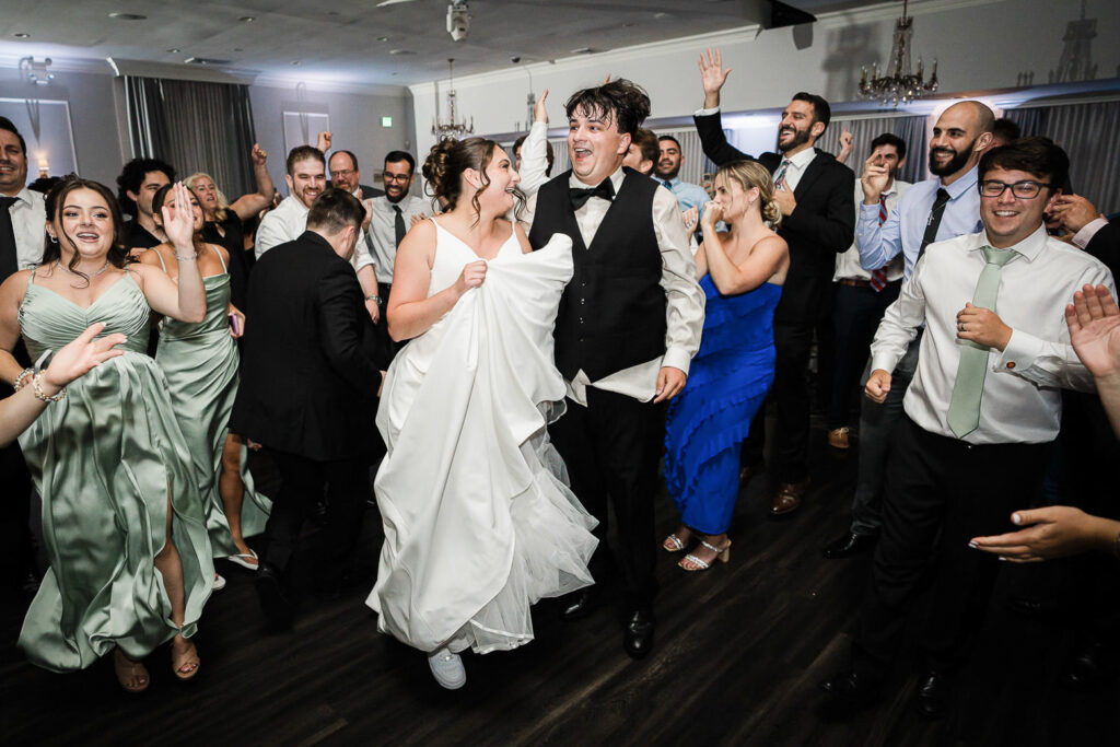 Newlyweds celebrating on packed dance floor at Mansion at Mountain Lakes reception