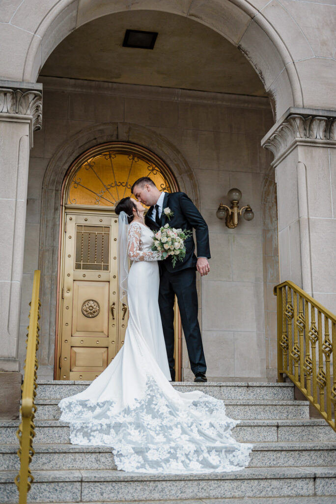Newlyweds on church steps with ornate gold door by Alex Kaplan Photography
