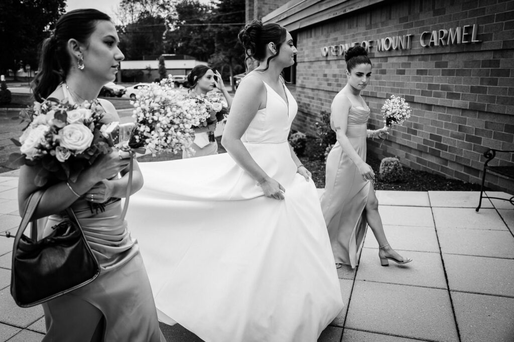 Bride and bridesmaids in sage green dresses walking outside Notre Dame of Mt Carmel Church Cedar Knolls