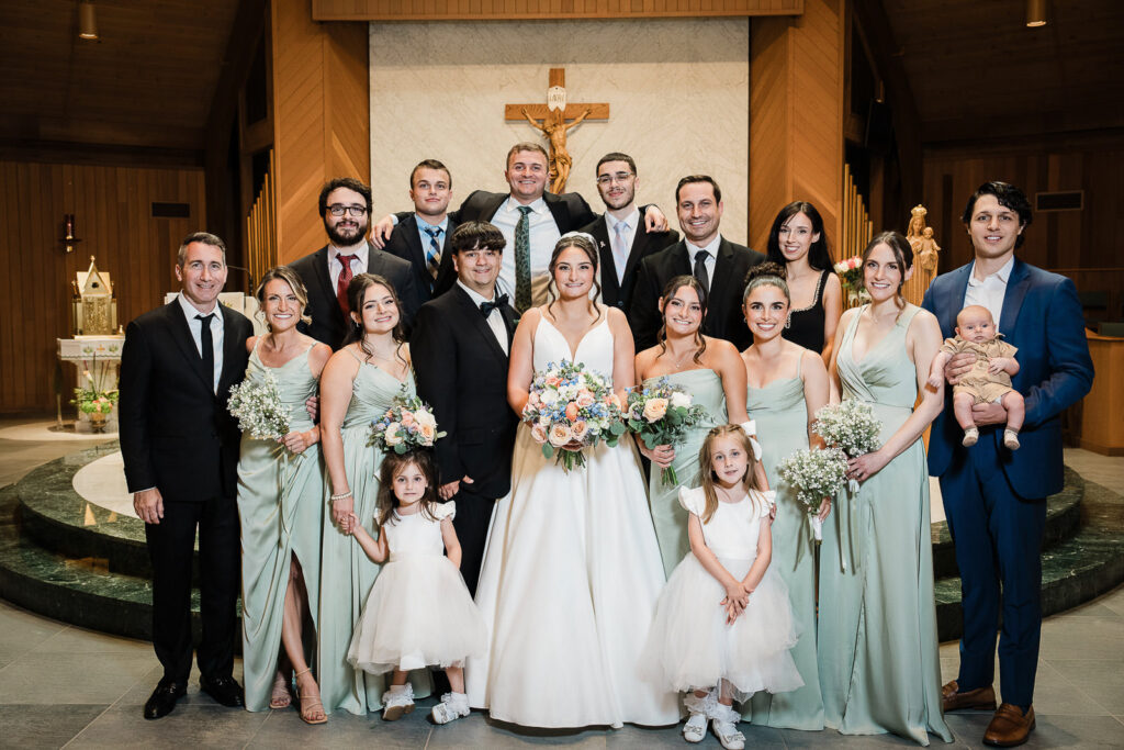 Complete bridal party with bridesmaids in sage green dresses and groomsmen at Notre Dame of Mt Carmel