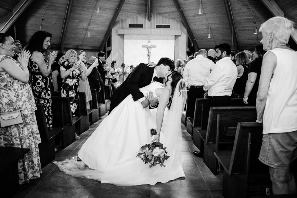Bride and groom dipping and kissing during recessional at Notre Dame of Mt Carmel Church Cedar Knolls