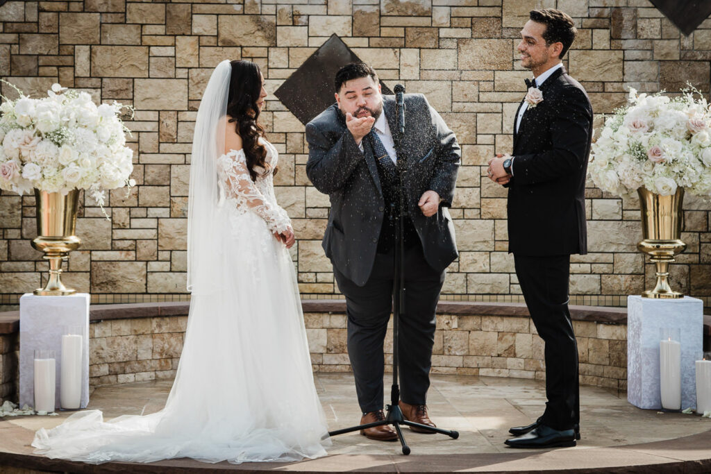 Officiant blessing couple with confetti during ceremony The Grand Totowa NJ wedding