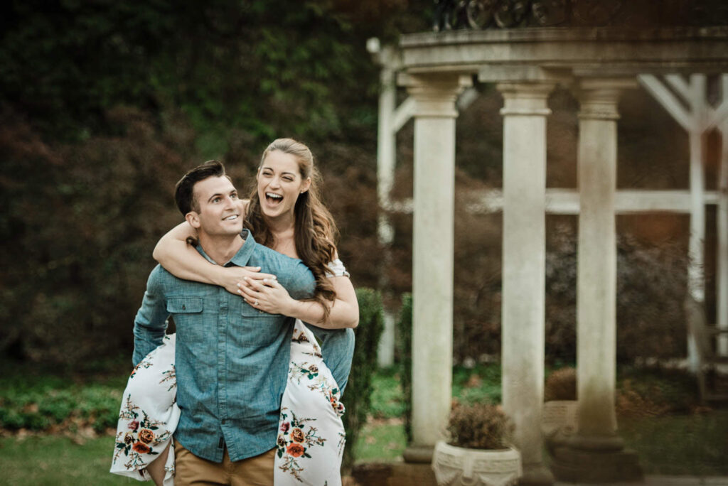 Playful piggyback moment captured during Hamilton NJ engagement photographer session at Sayen Gardens
