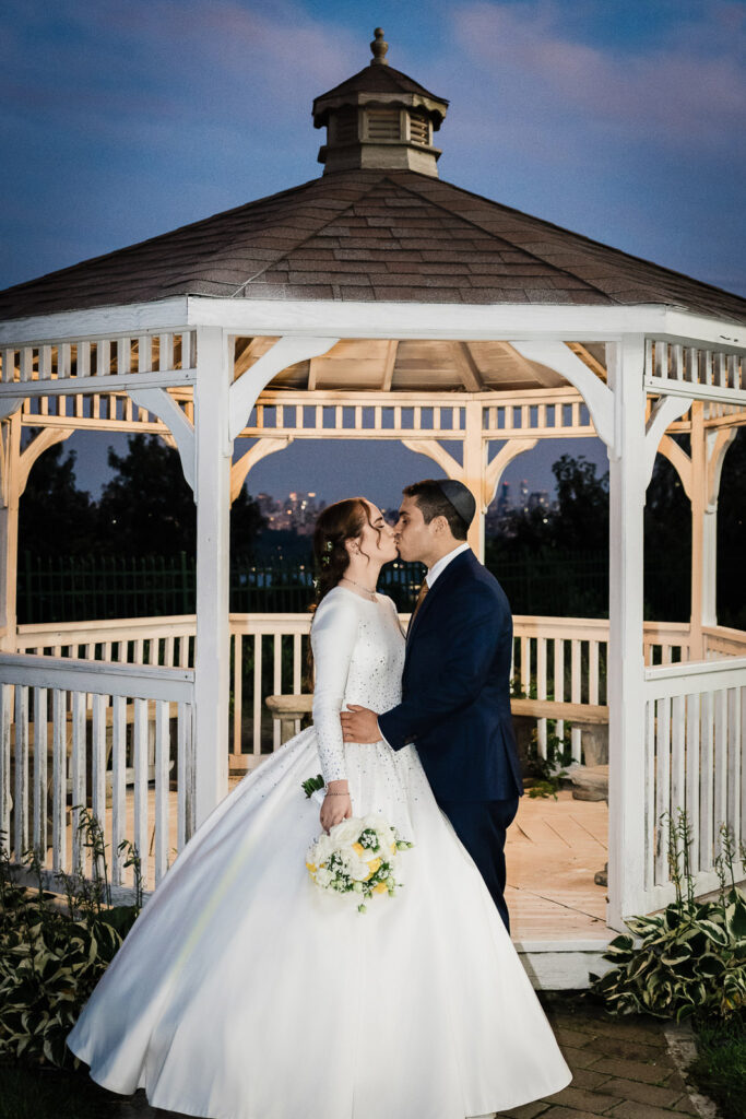 Romantic couple kiss at gazebo during blue hour at Riverview Ballroom Cliffside Park NJ wedding