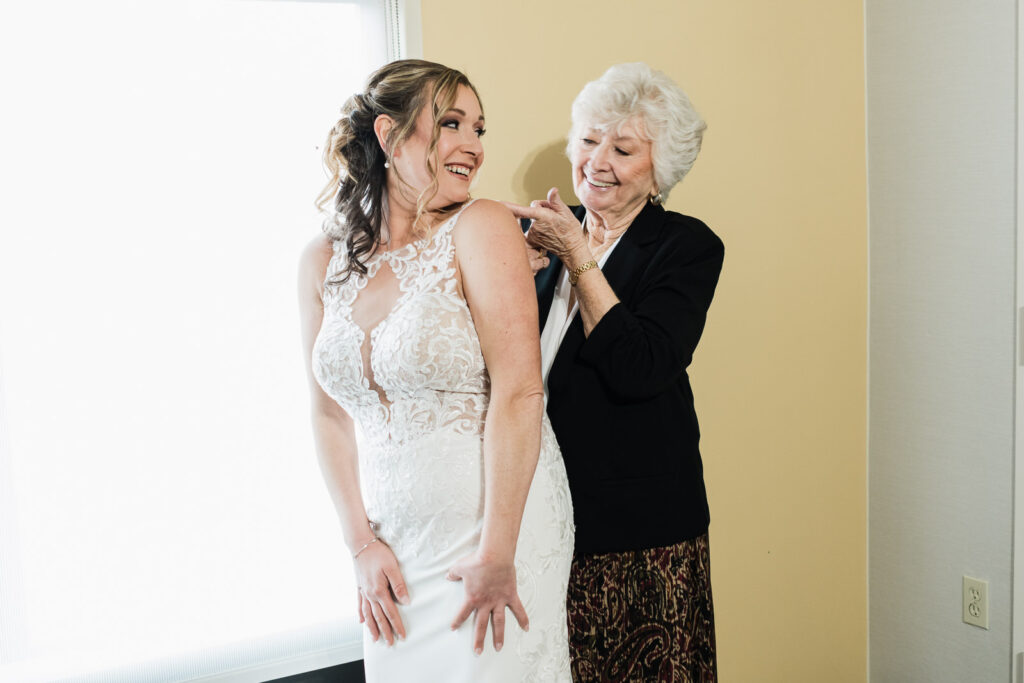 Grandmother adjusting bride's dress before ceremony Windsor Ballroom New Jersey