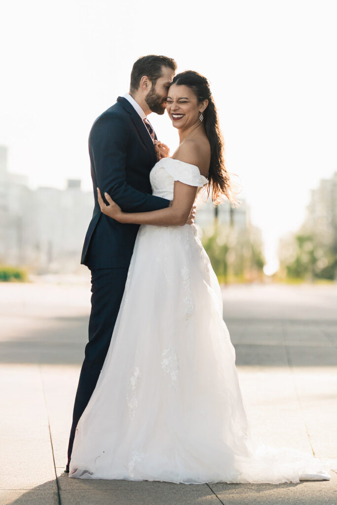Joanna and Alex embracing at Port Imperial waterfront with NYC skyline backdrop romantic wedding photography West New York