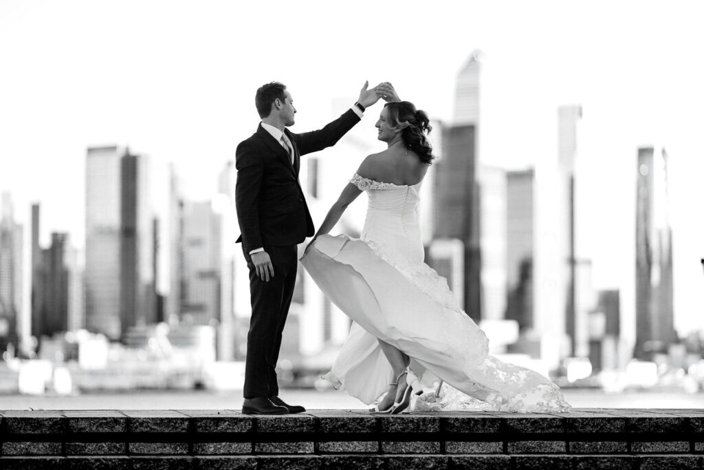 Black and white Luz and Stephan dancing on waterfront with Manhattan skyline dramatic wedding photography Port Imperial West New York