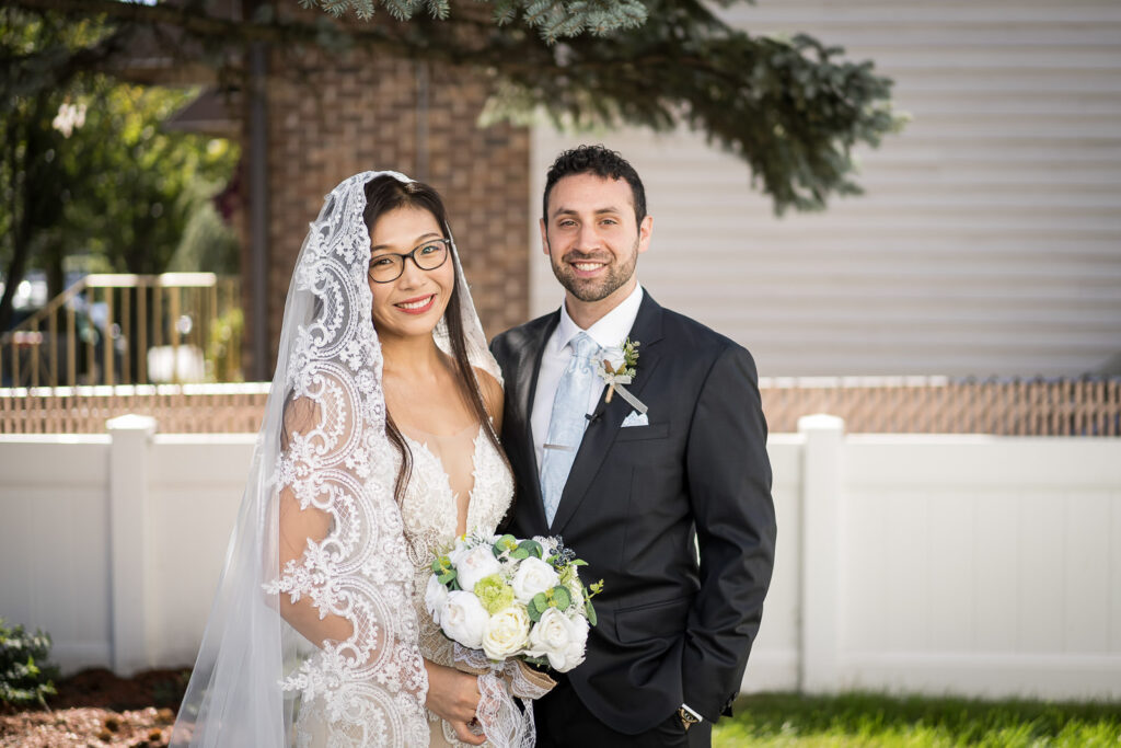 Rob and Ruby couple portrait after first look at Fair Lawn home wedding with cathedral veil and light blue wedding colors