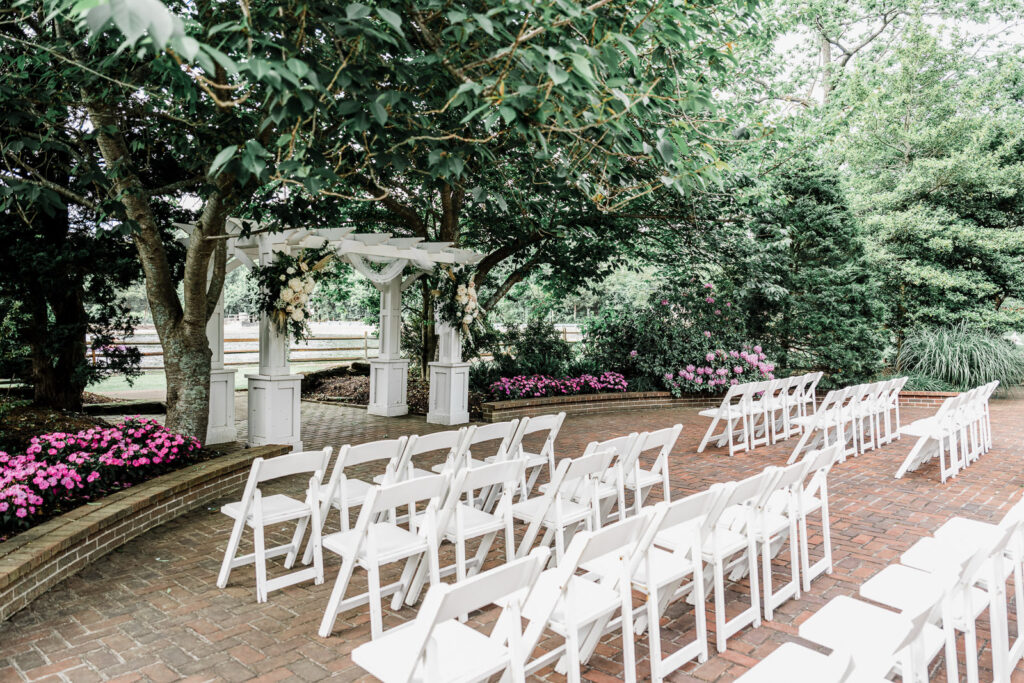 Empty outdoor ceremony space with white folding chairs and decorated pergola at Smithville Inn wedding venue in New Jersey
