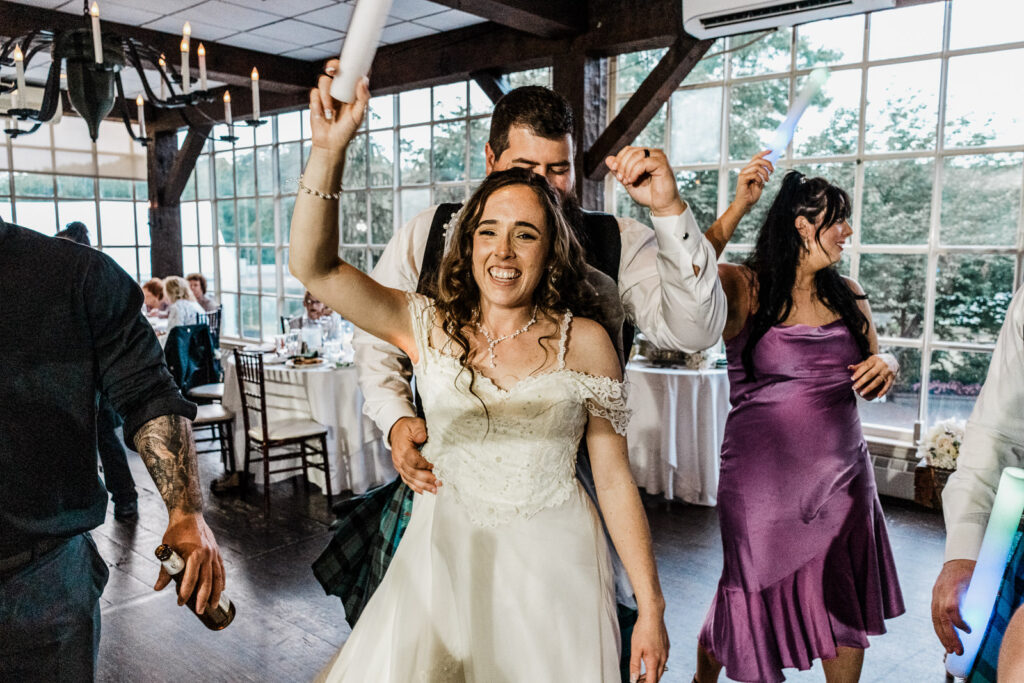 Bride with arms raised celebrating and dancing with joy at Smithville Inn reception in Absecon New Jersey wedding