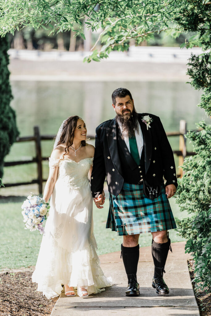 Natural portrait of bride and Scottish groom walking together on tree-lined pathway at Smithville Inn wedding venue in New Jersey