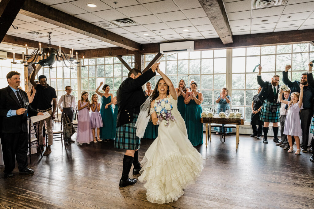 grand-entrance-couple-celebrating-reception-nj.jpgJoyful grand entrance of bride and Scottish groom with arms raised as guests cheer at Smithville Inn reception in New Jersey