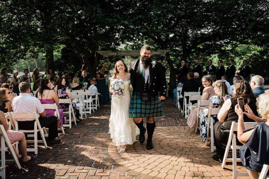 Newlyweds walking down brick aisle at Smithville Inn lakeside ceremony by Alex Kaplan