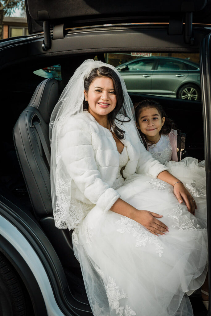 Bride with flower girl in limo before ceremony photographed by Alex Kaplan