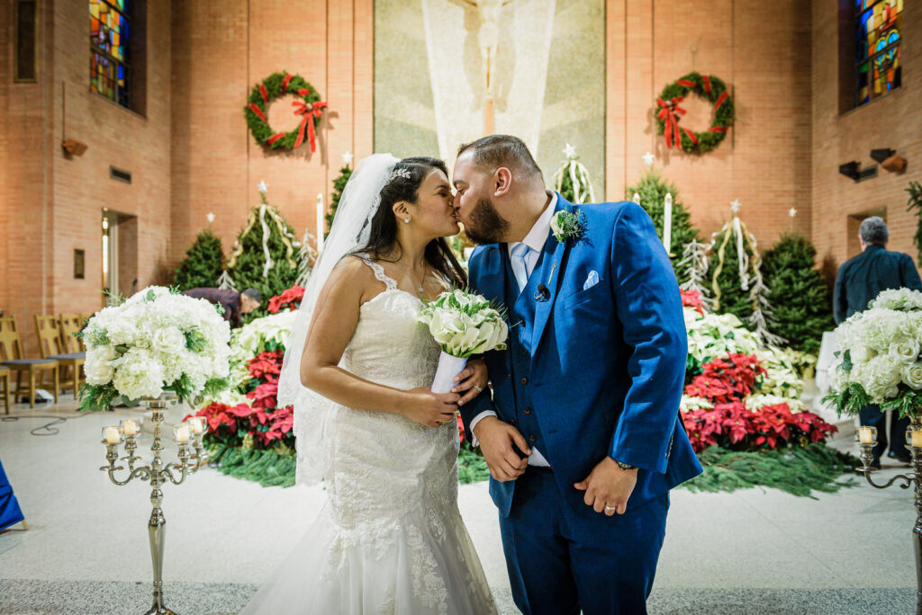 Newlyweds kissing at St Theresa Church with Christmas decorations