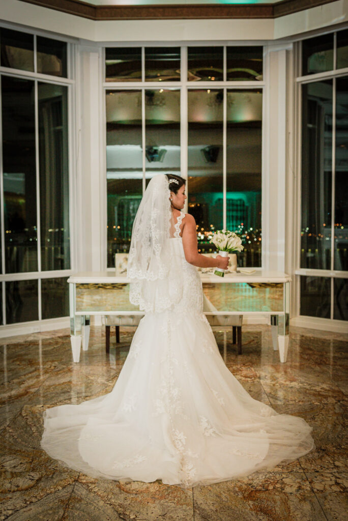 Bride with cathedral veil by bay windows at Westmount Country Club