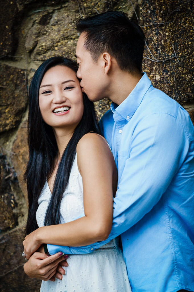 Candid laughter moment with forehead kiss during Deep Cut Gardens engagement photography session in New Jersey