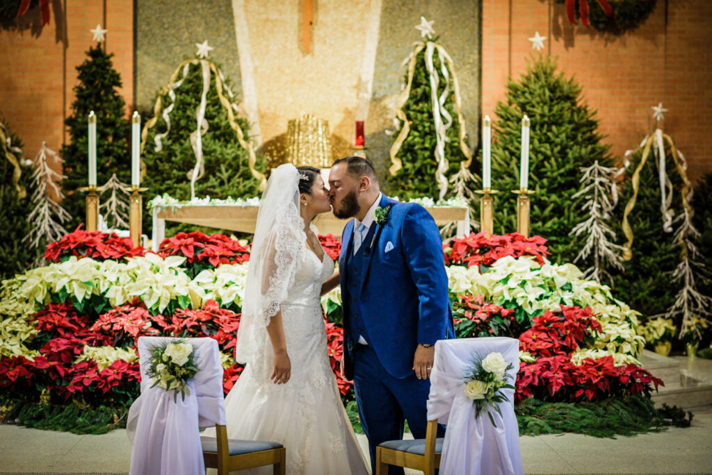 First kiss at St Theresa Church altar with Christmas poinsettias