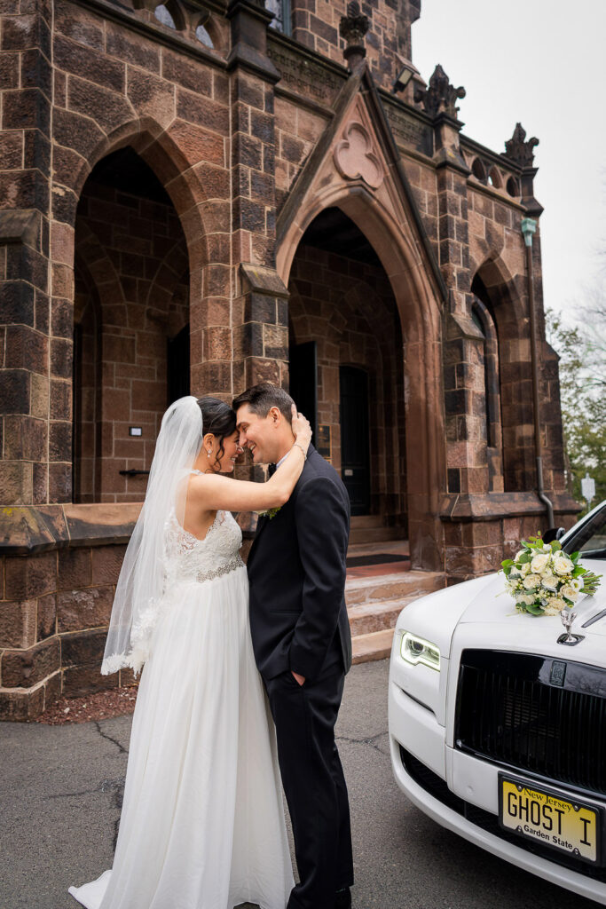 Intimate moment between bride and groom in front of luxury Rolls Royce at Kirkpatrick Chapel exterior, photographed by Alex Kaplan