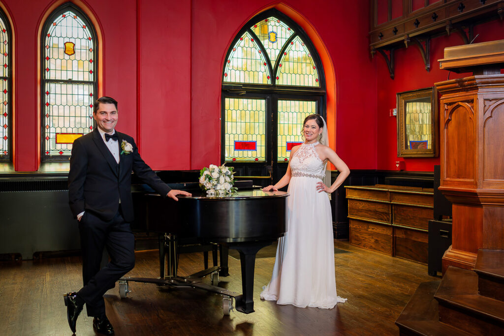 Elegant wedding portrait by grand piano at Kirkpatrick Chapel with colorful Gothic stained glass windows, New Brunswick wedding by Alex Kaplan