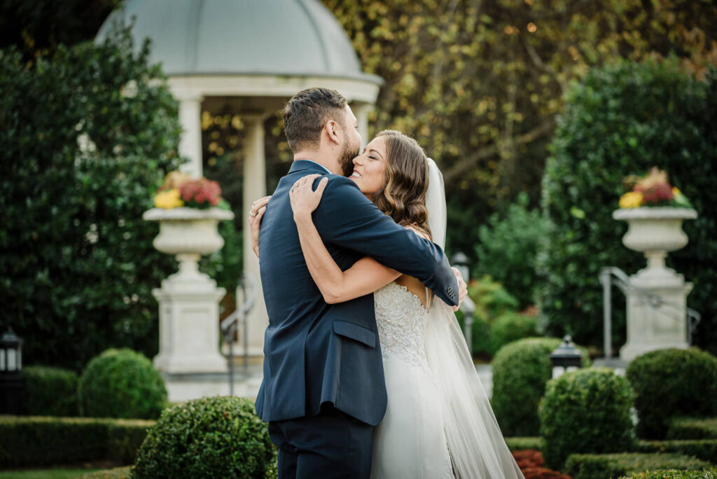 Bride and groom embracing in Park Chateau formal gardens during fall wedding East Brunswick