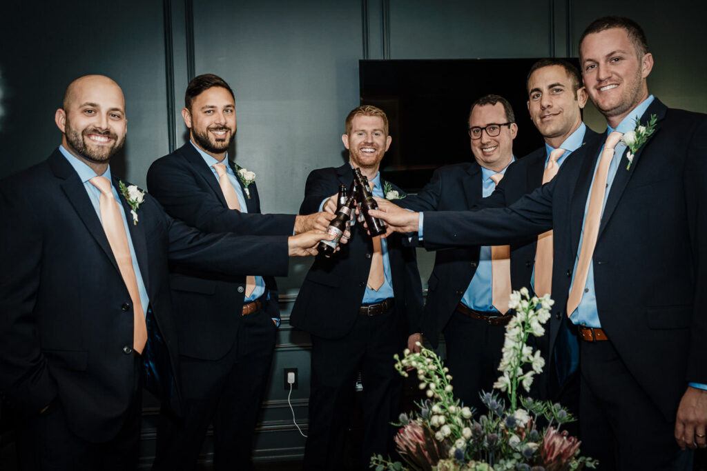 Groomsmen toasting with beer bottles at Park Chateau wedding in East Brunswick